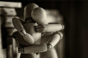 abbraccio simbolico tra due figure in legno
